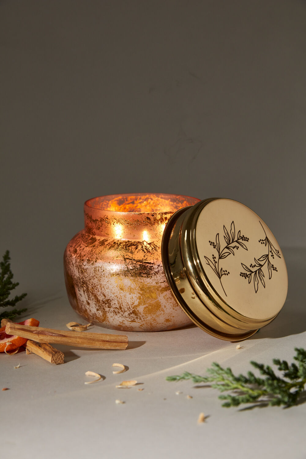 Enchanted Forest Candle in gold glass container with etched lid open and lighted